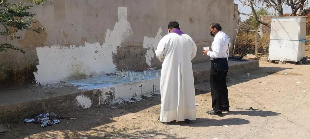 Un sacerdote y un ciudadano oran por el descanso de las víctimas del multihomicidio ocurrido en la colonia La Jauja, Tonalá. Foto: Internet.