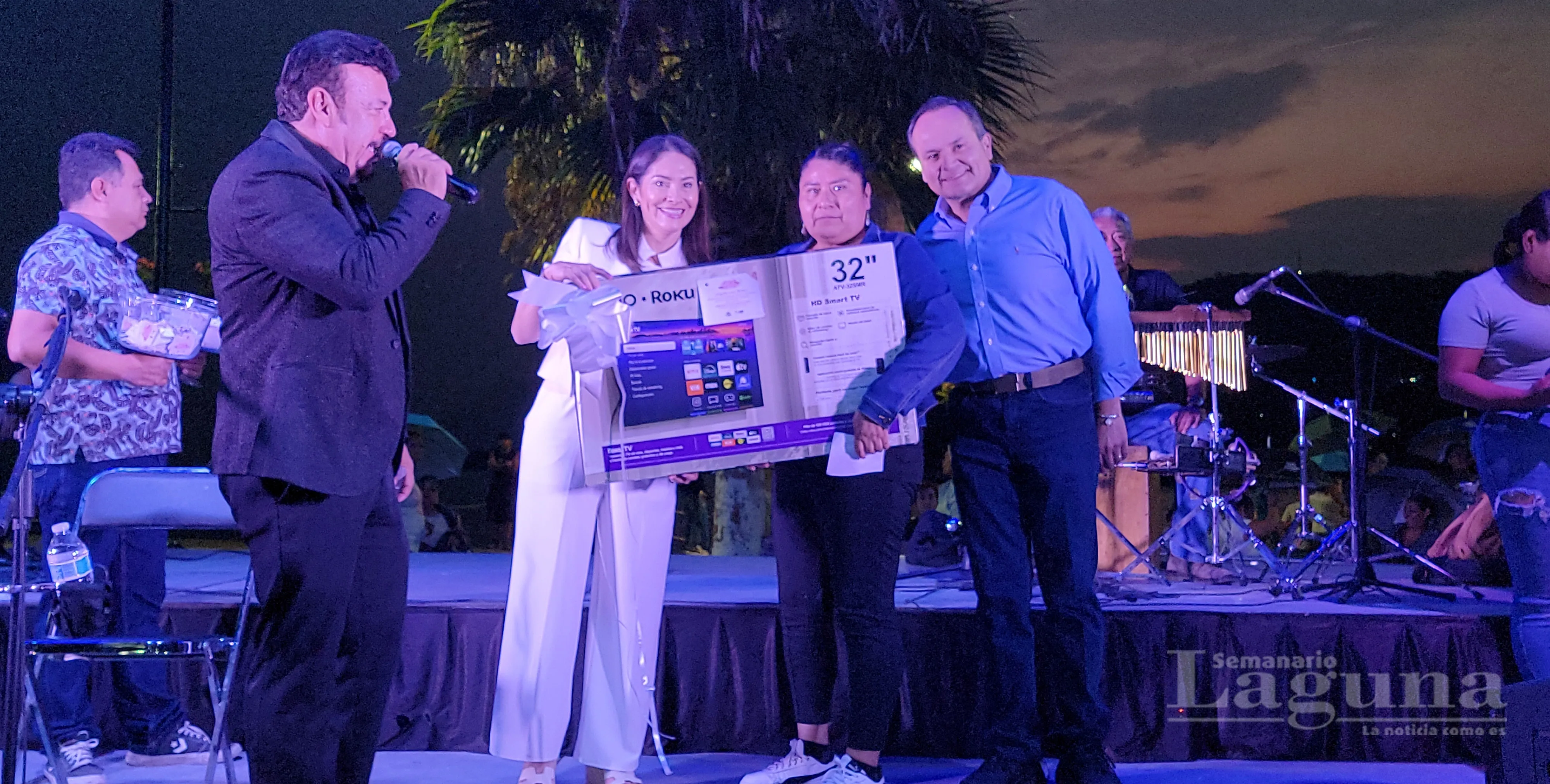 El alcalde de Chapala, Alejandro de Jesús Aguirre Curiel, y la presidenta del DIF municipal, Erika Eryn Torres,  hacen entrega de un televisor a una de las madres ganadoras durante el festejo.