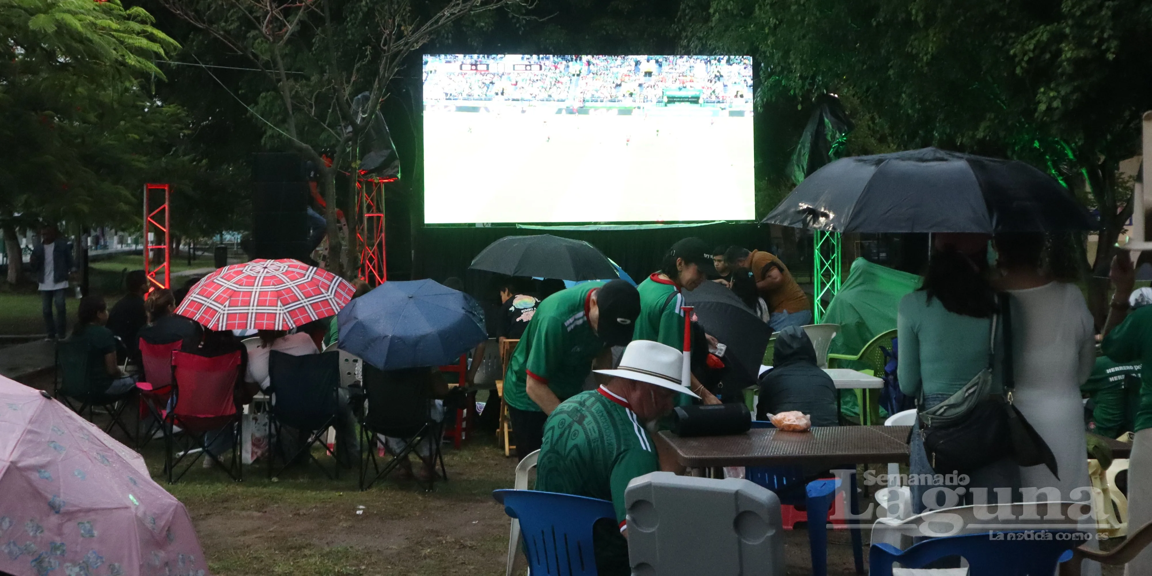 Aficionados con paraguas durante el inicio de la transmisión del partido México contra Chequia en el malecón de Ajijic. Foto: Sofía Medeles.