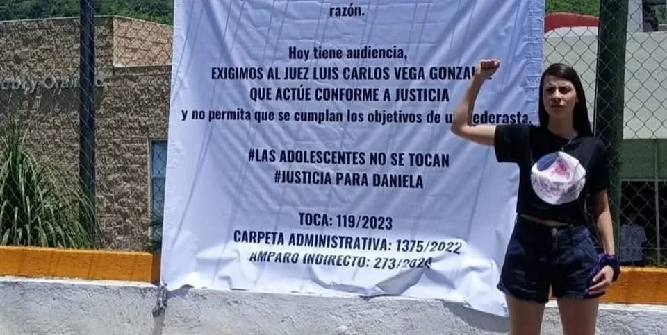 Daniela frente a una lona en la que exhibe su caso afuera del CEINJURE Chapala. Foto: Cortesía.